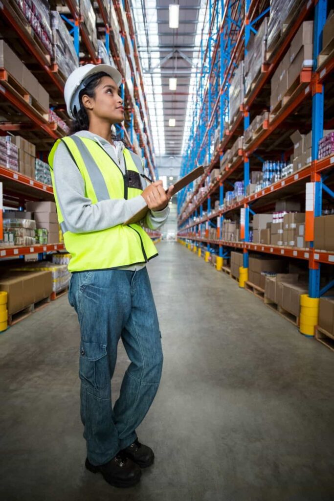 Female warehouse worker checking inventory at wholesale distributors in USA warehouse facility