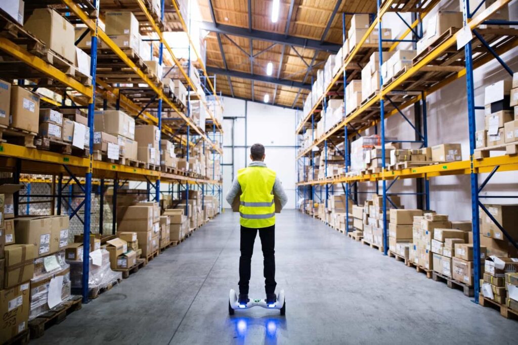"Male warehouse worker using a hoverboard – Trusted UK wholesale supplier for Amazon FBA and retail businesses."